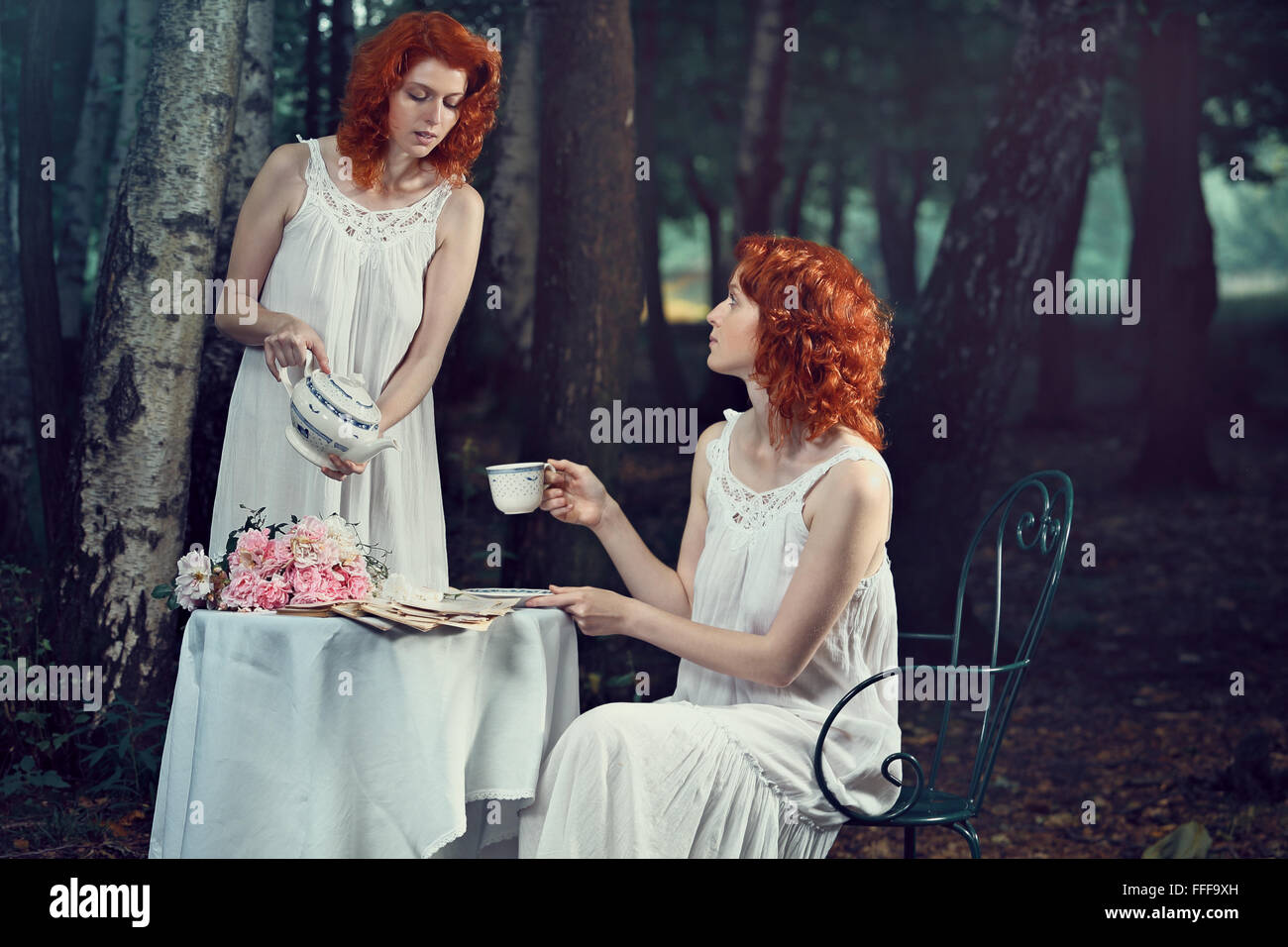 Bella donna redhead che serve tè al twin . Fantasia e surreale Foto Stock