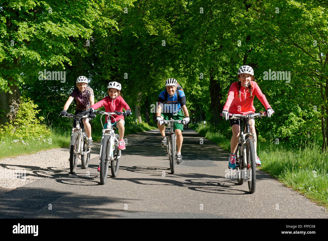 Famiglia con bambini equitazione biciclette su avenue, Qualzow, Müritz National Park, Meclemburgo Lake District Foto Stock