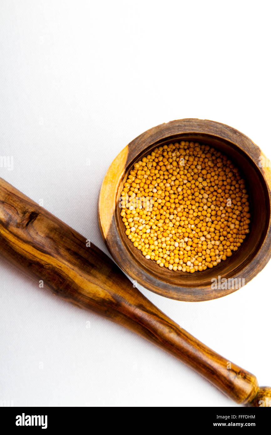 Un legno colorato mortaio e pestello con seme di senape Foto Stock