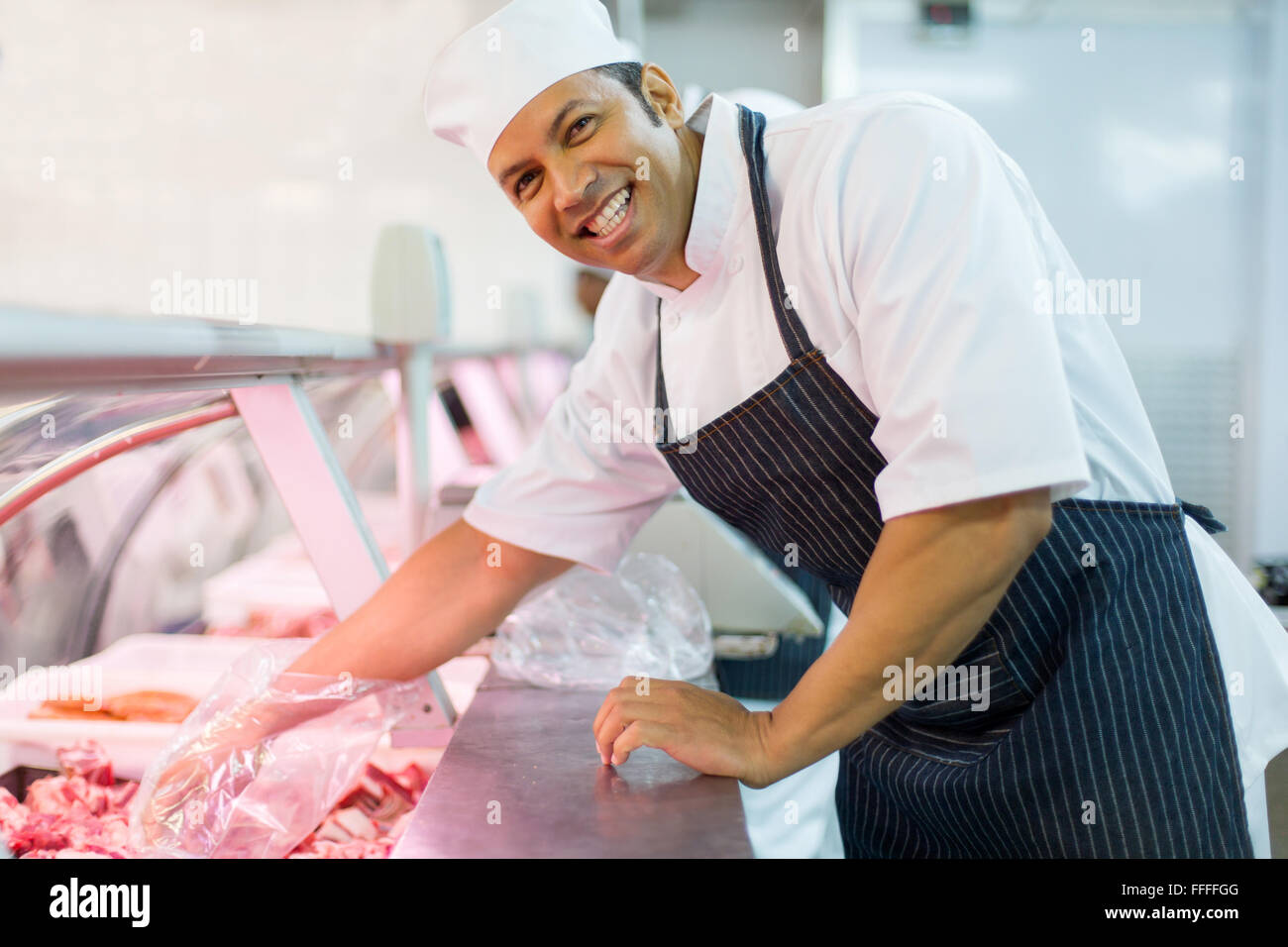 Allegro metà età butcher picking carni fresche Foto Stock