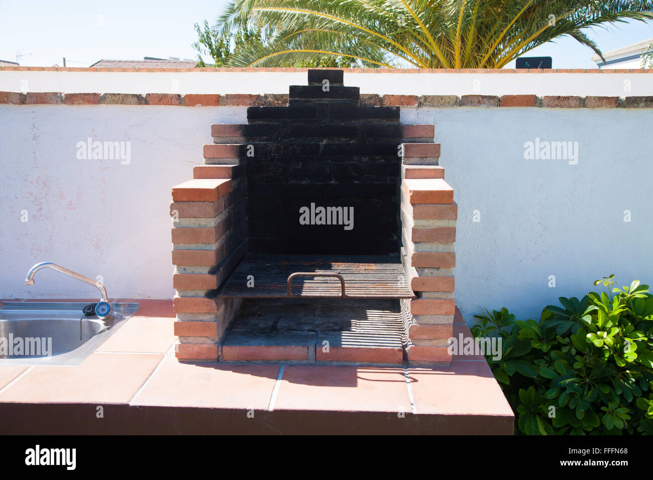 Base barbecue esterno realizzato con mattoni di colore arancione rusty grill e lavanderia in metallo Foto Stock