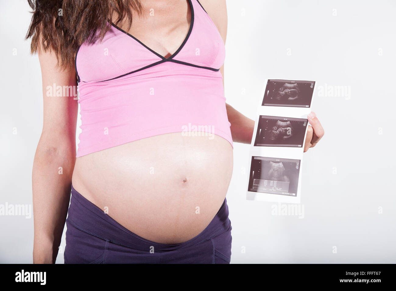 Otto mesi di gravidanza donna partorì ventre maglia rosa viola pantaloni  con ultrasuoni baby scansione nella sua mano isolato su bianco Foto stock -  Alamy