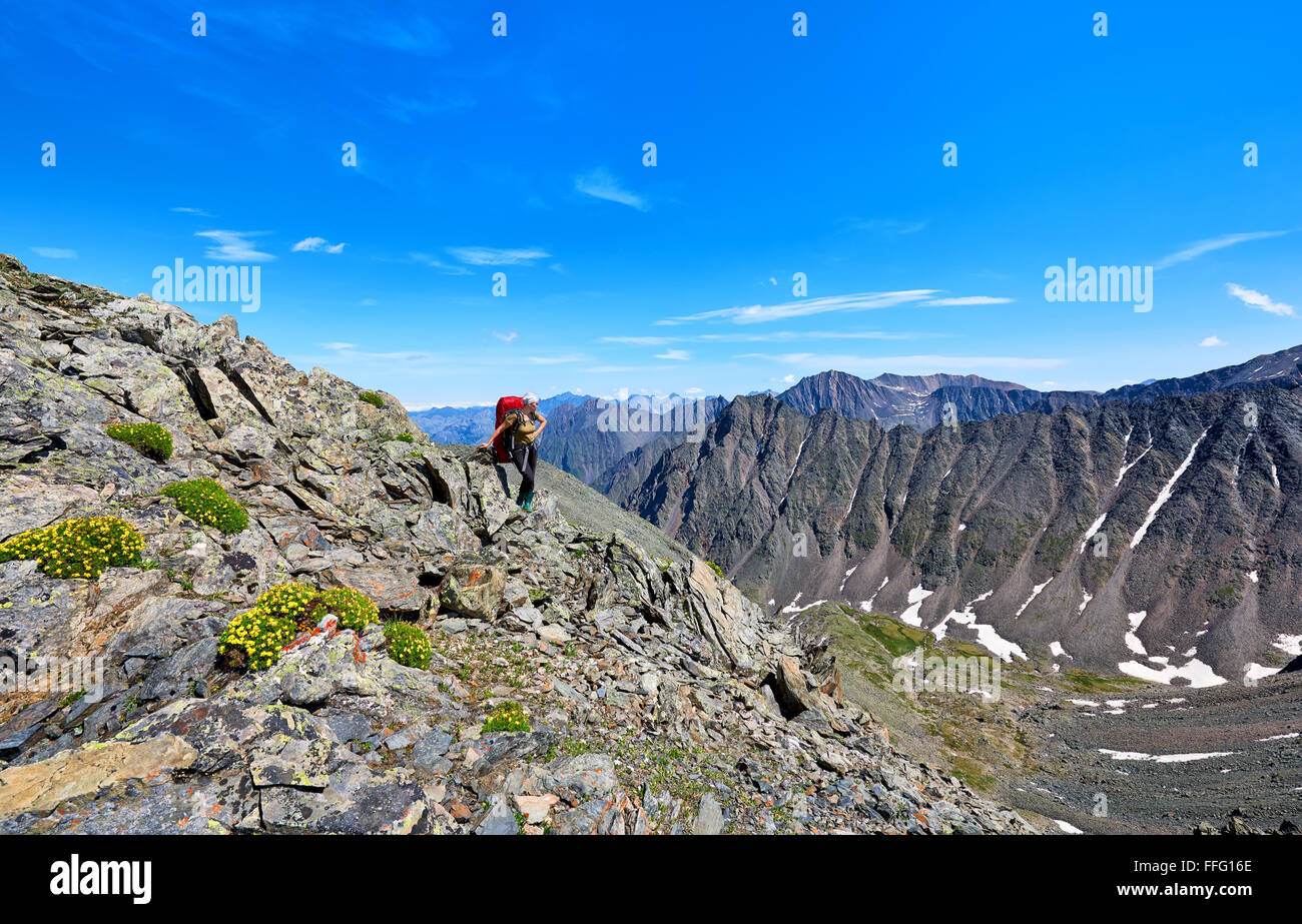 Pass hopping. Donna con uno zaino sullo sfondo delle cime di montagna in alta montagna . Sayan orientale . La Russia Foto Stock