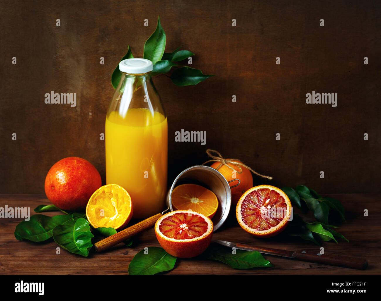 Natura morta con frutta di arancia e il succo in una bottiglia di vetro su un tavolo di legno. Lo stile di pittura. Foto Stock