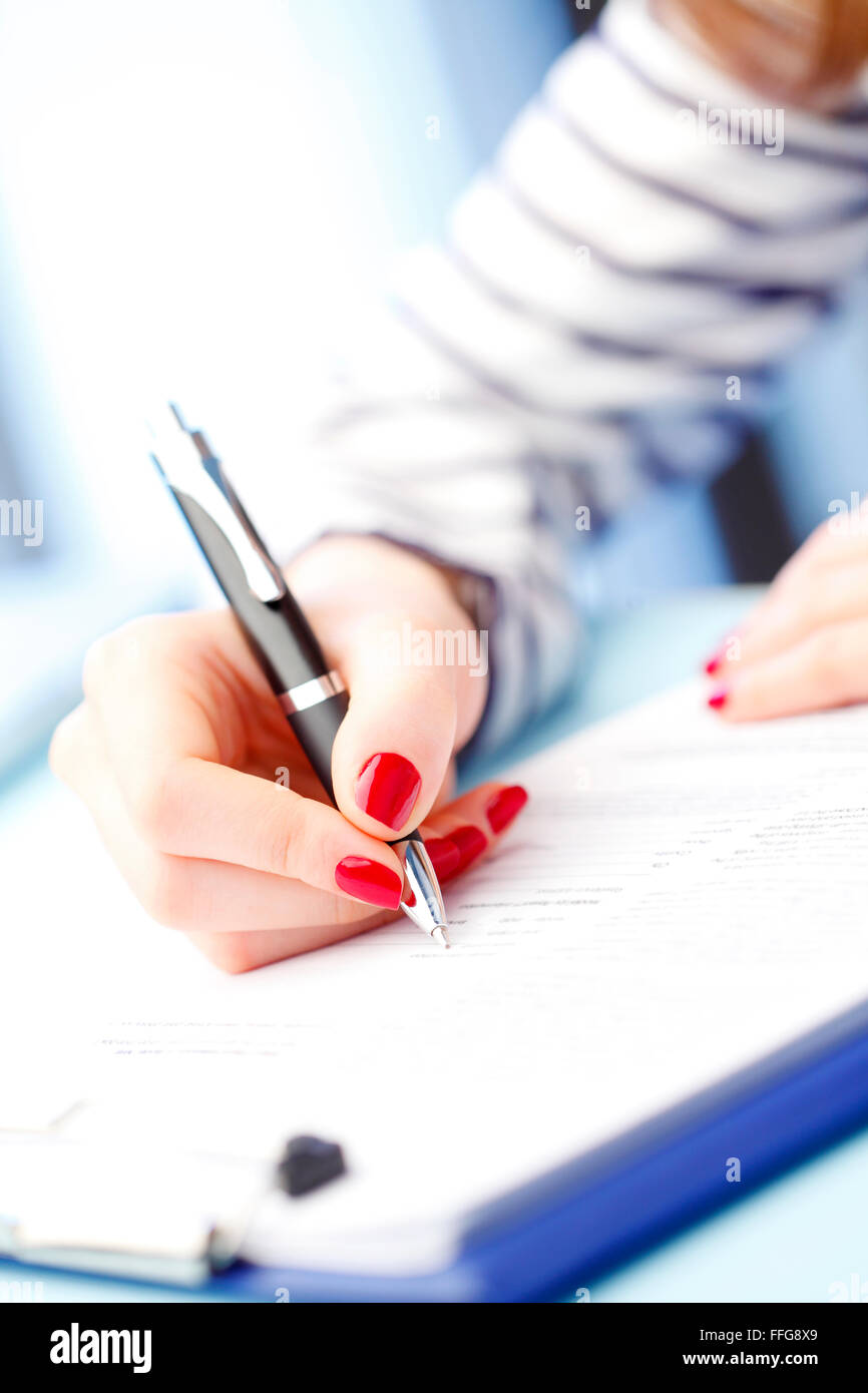 Close-up ritratto di giovane donna seduta alla scrivania e riempimento test IQ mentre è seduto alla scrivania. Foto Stock