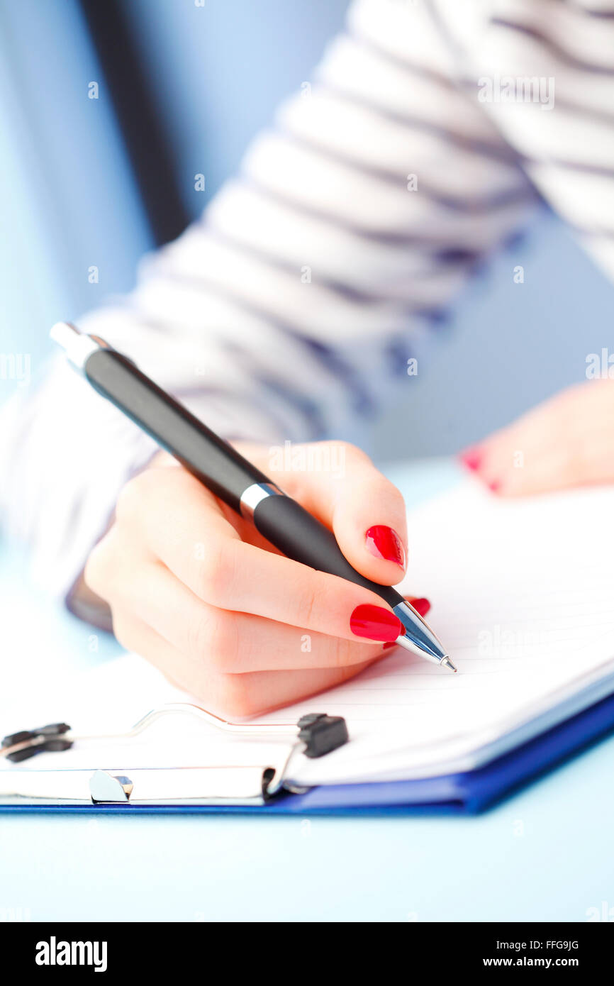 Close-up ritratto di giovane donna seduta alla scrivania e riempimento test IQ mentre è seduto alla scrivania. Foto Stock