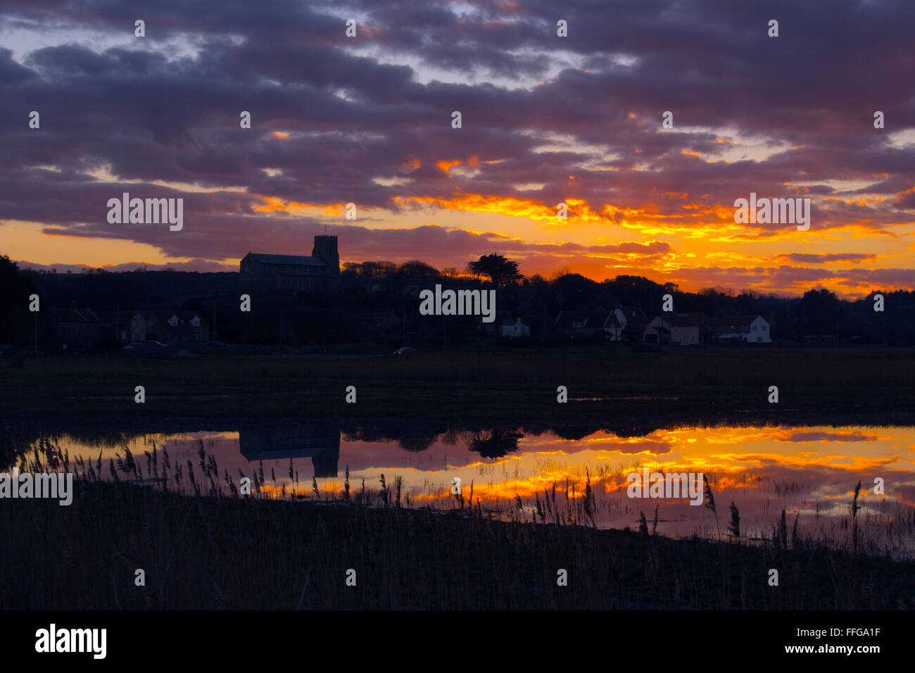 Salthouse villaggio chiesa e paludi allagate in primo piano al tramonto Foto Stock