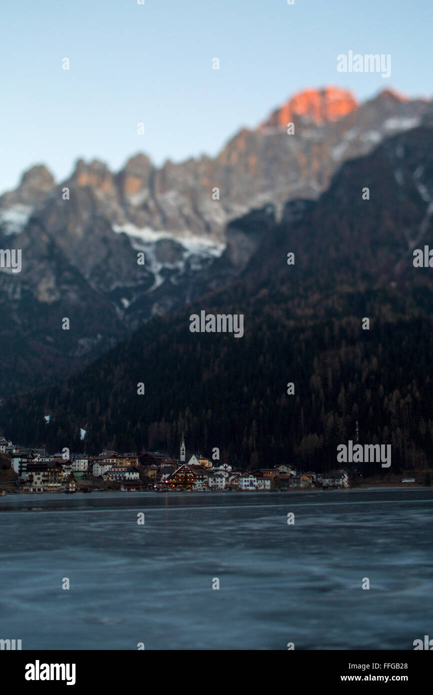 Il villaggio e il lago di Alleghe al tramonto con il comprensorio sciistico del Civetta in background. Foto Stock