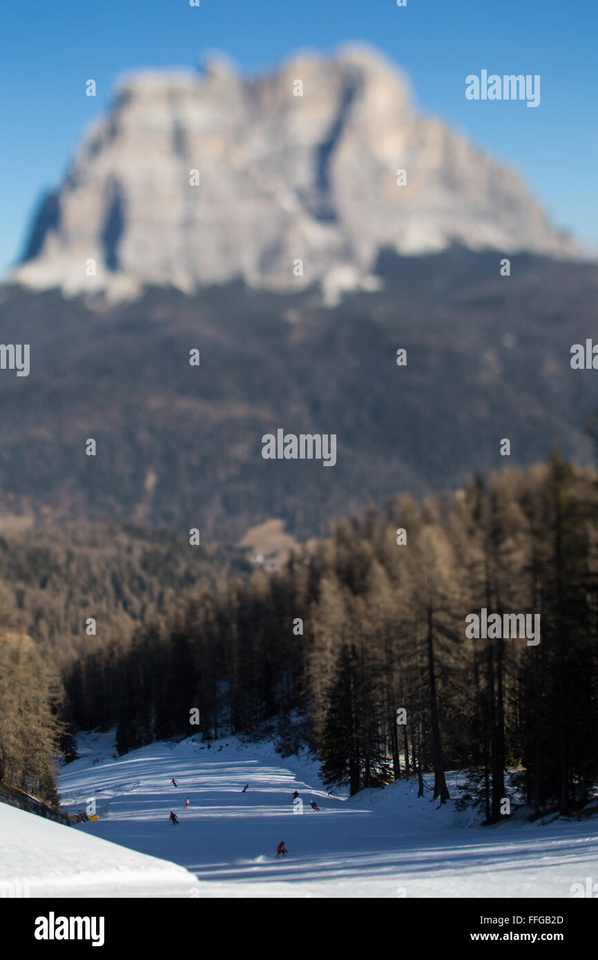 Un tilt shift vista di sciatori scendere una pista da sci in Zoldo area del comprensorio sciistico del Civetta ski resort con il Monte Pelmo in background Foto Stock