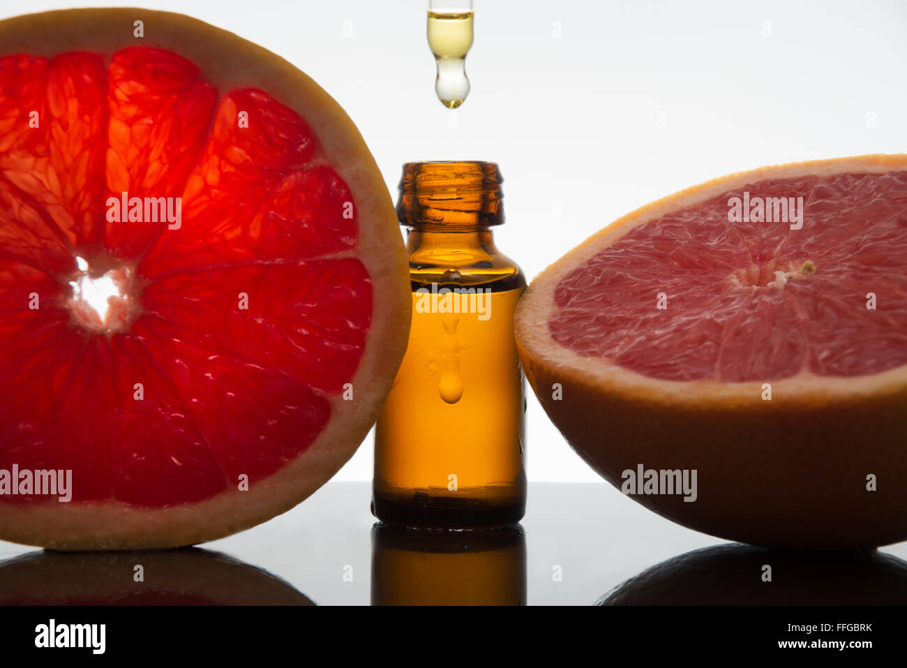 Olio essenziale flacone di vetro ambrato con fette di pompelmo, con contagocce Foto Stock