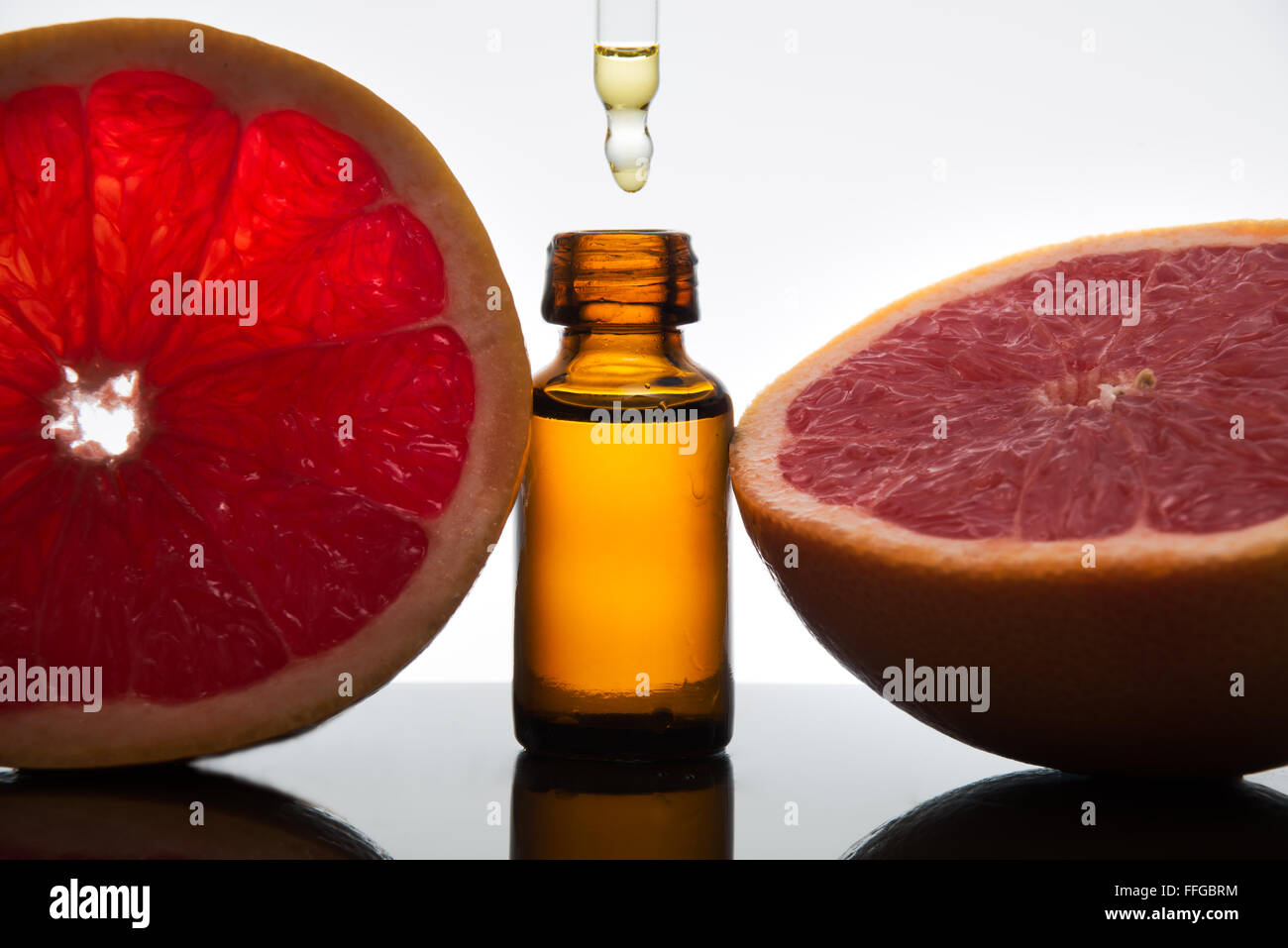 Olio essenziale flacone di vetro ambrato con fette di pompelmo, con contagocce Foto Stock