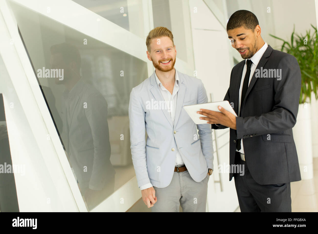 Moderni giovani uomini con la compressa in ufficio Foto Stock
