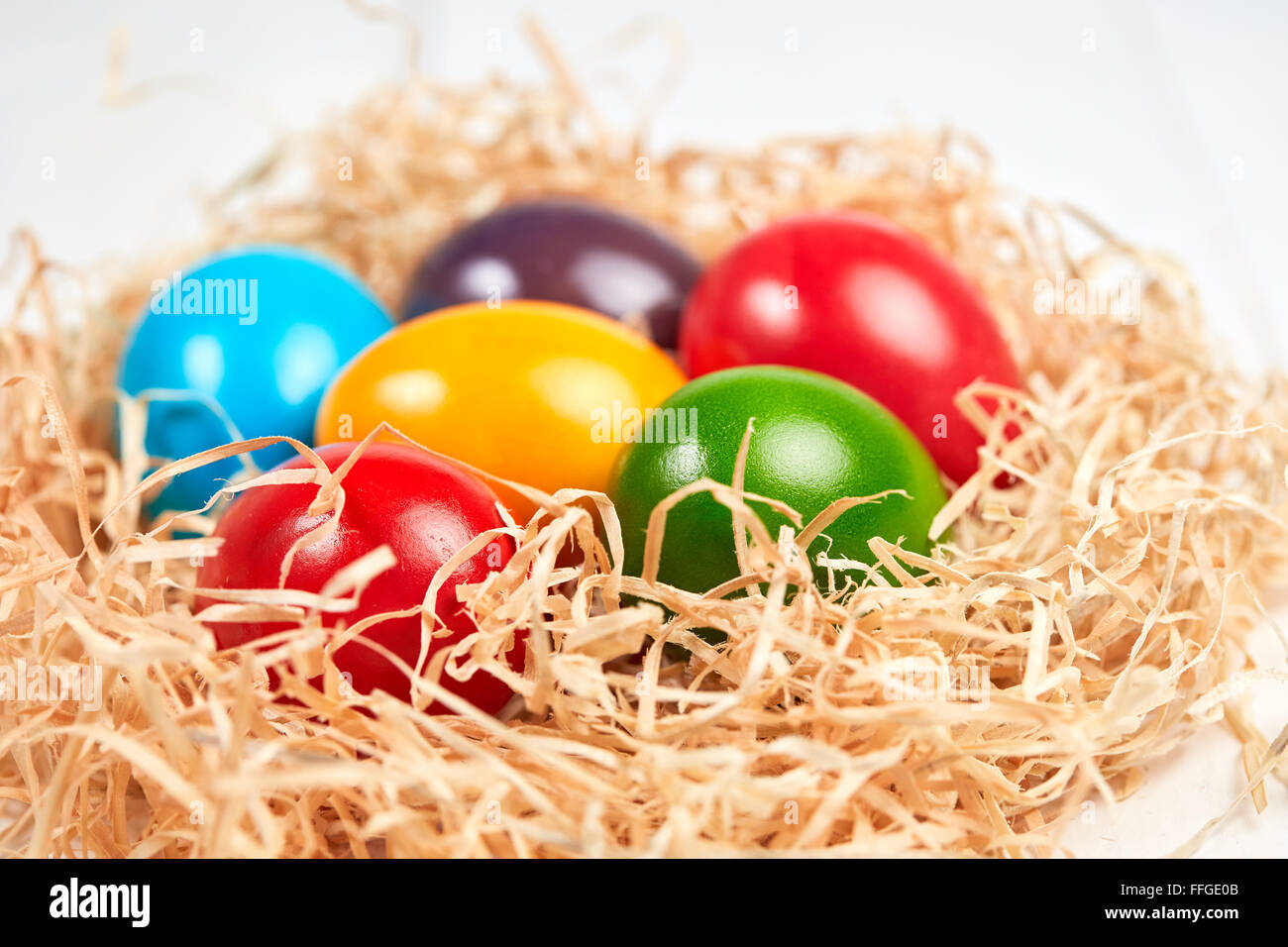 Primo piano della pasqua isolato il nido di paglia con colori diversi le uova di pasqua. Foto Stock