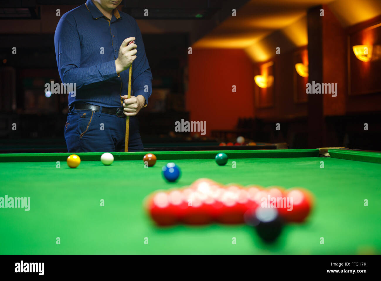Giovane uomo linee fino il suo tiro come egli rompe le sfere per iniziare il gioco del biliardo Foto Stock