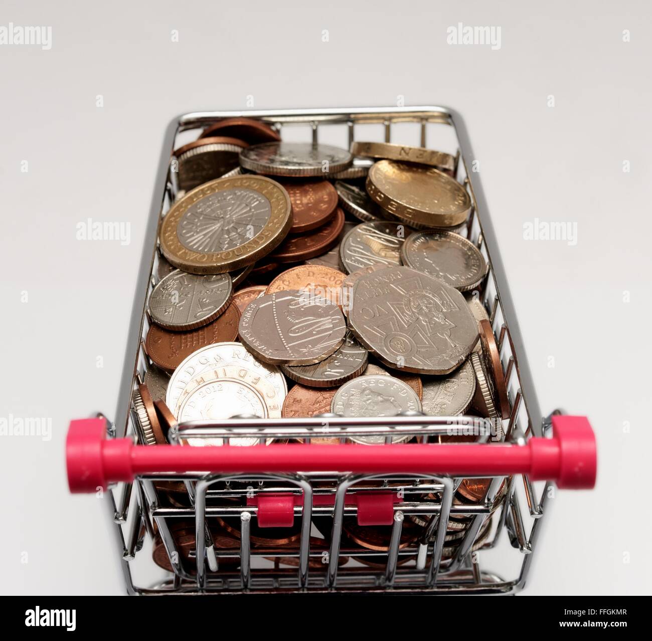 Piccolo supermercato carrello della spesa con le monete all'interno. Costo della vita concetto Foto Stock