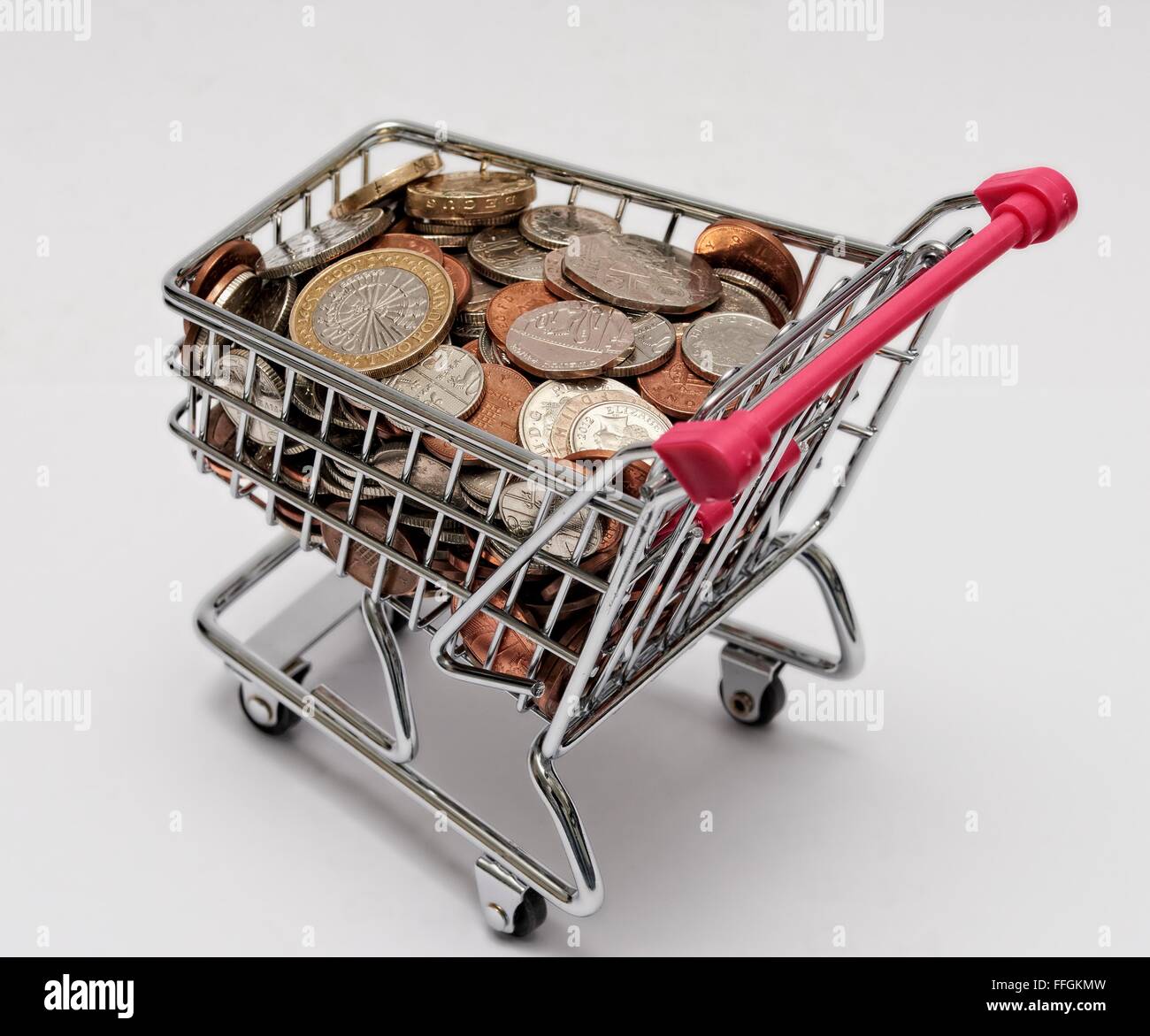 Piccolo supermercato carrello della spesa con le monete all'interno. Costo della vita concetto Foto Stock