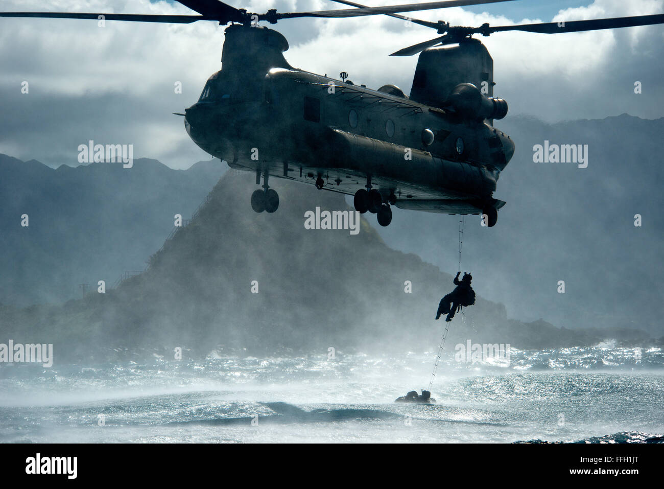 Un aviatore dal ventiduesimo Tattiche speciali Squadron salite in un U.S. Esercito CH-47 Chinook durante helo-colata le azioni di formazione al largo delle Hawaii. I cinque piedi di ocean si rigonfia fornito gli operatori con un ambiente stimolante. Foto Stock