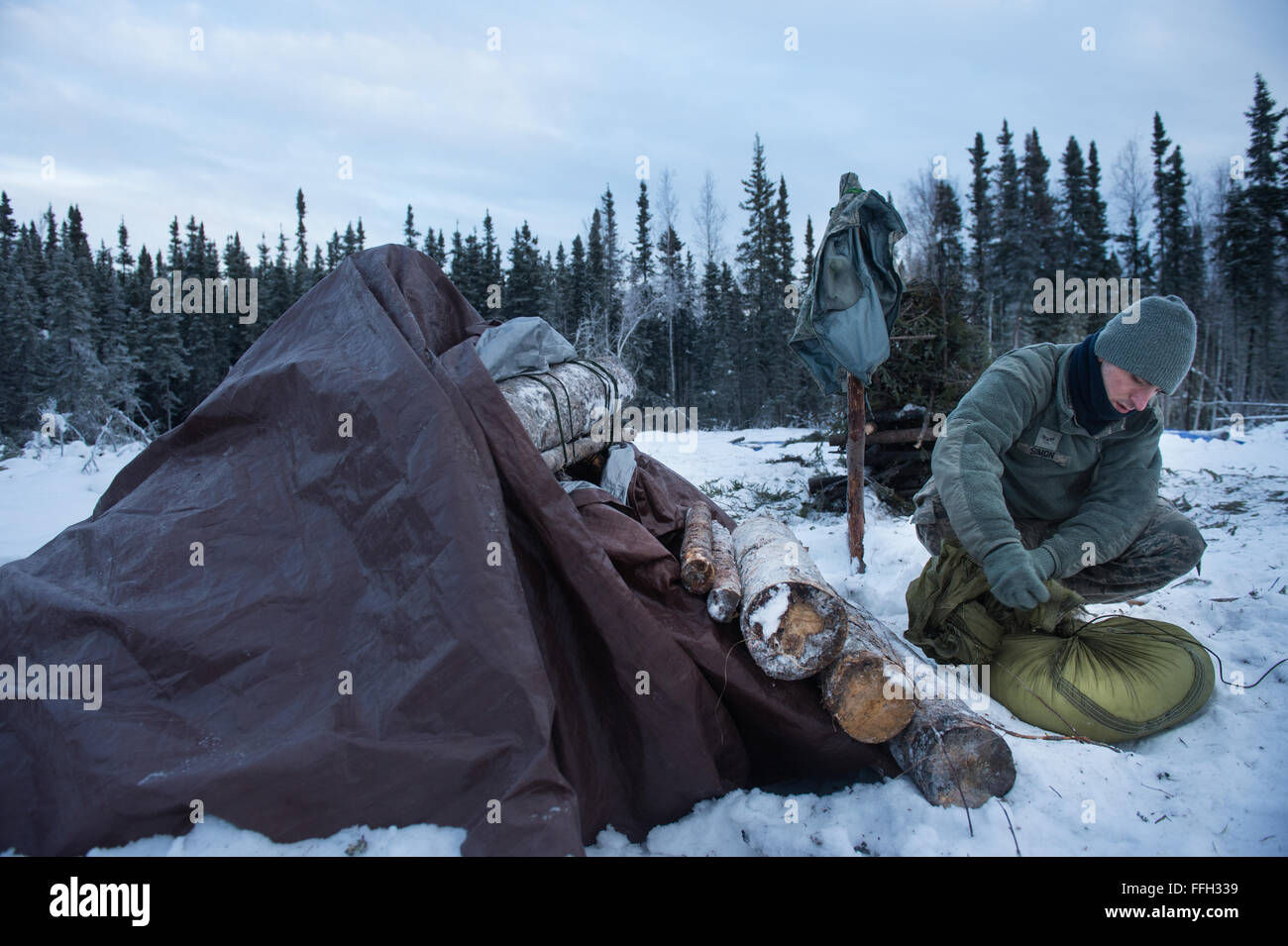 Airman 1. Classe Ray Simon, 3a supporto di manutenzione Squadron, capo equipaggio, prepara la copertura per il suo termalizzati telaio a riparo durante la sopravvivenza artica formazione a Eielson Air Force Base in Alaska. Il telaio a ricovero è progettata per tenere il sopravvissuto caldo e asciutto a sopportare dure la notte artica. Foto Stock