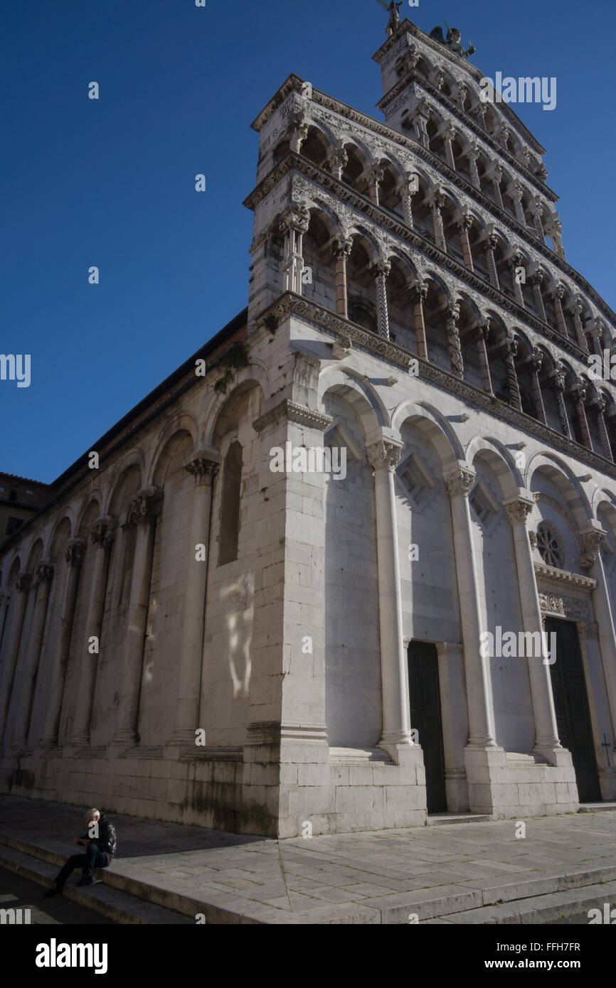 Uomo seduto a fianco di San Michele in Foro basilica di Lucca Foto Stock