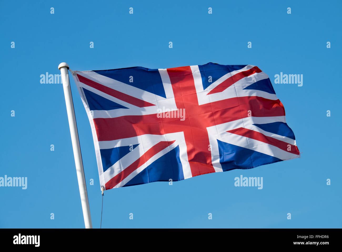 La bandiera europea svolazzanti sulla cima di un pennone bianco su una soleggiata giornata contro un cielo blu chiaro Foto Stock
