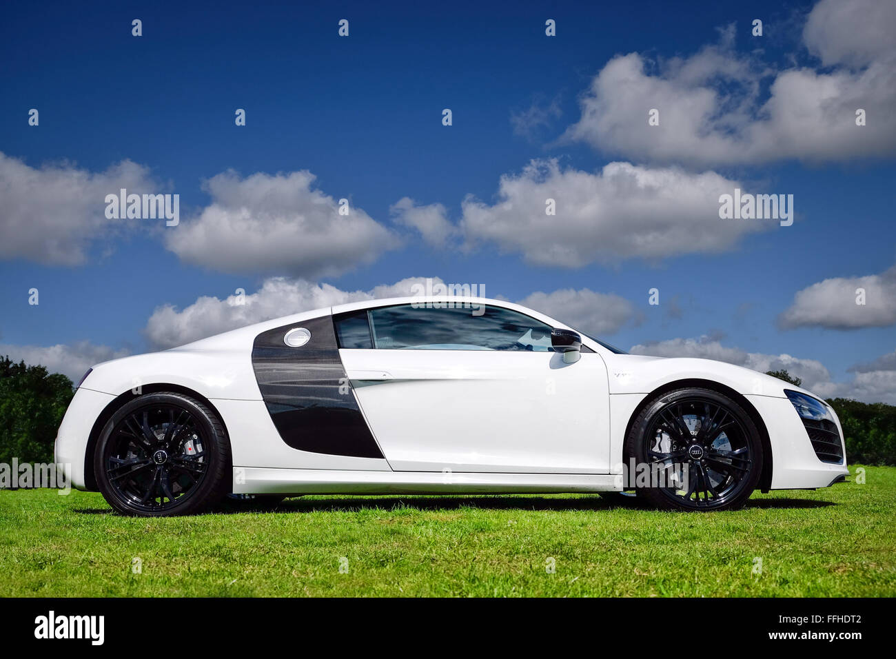 Un bianco Audi R8 in una giornata di sole sorgeva sull'erba Foto Stock