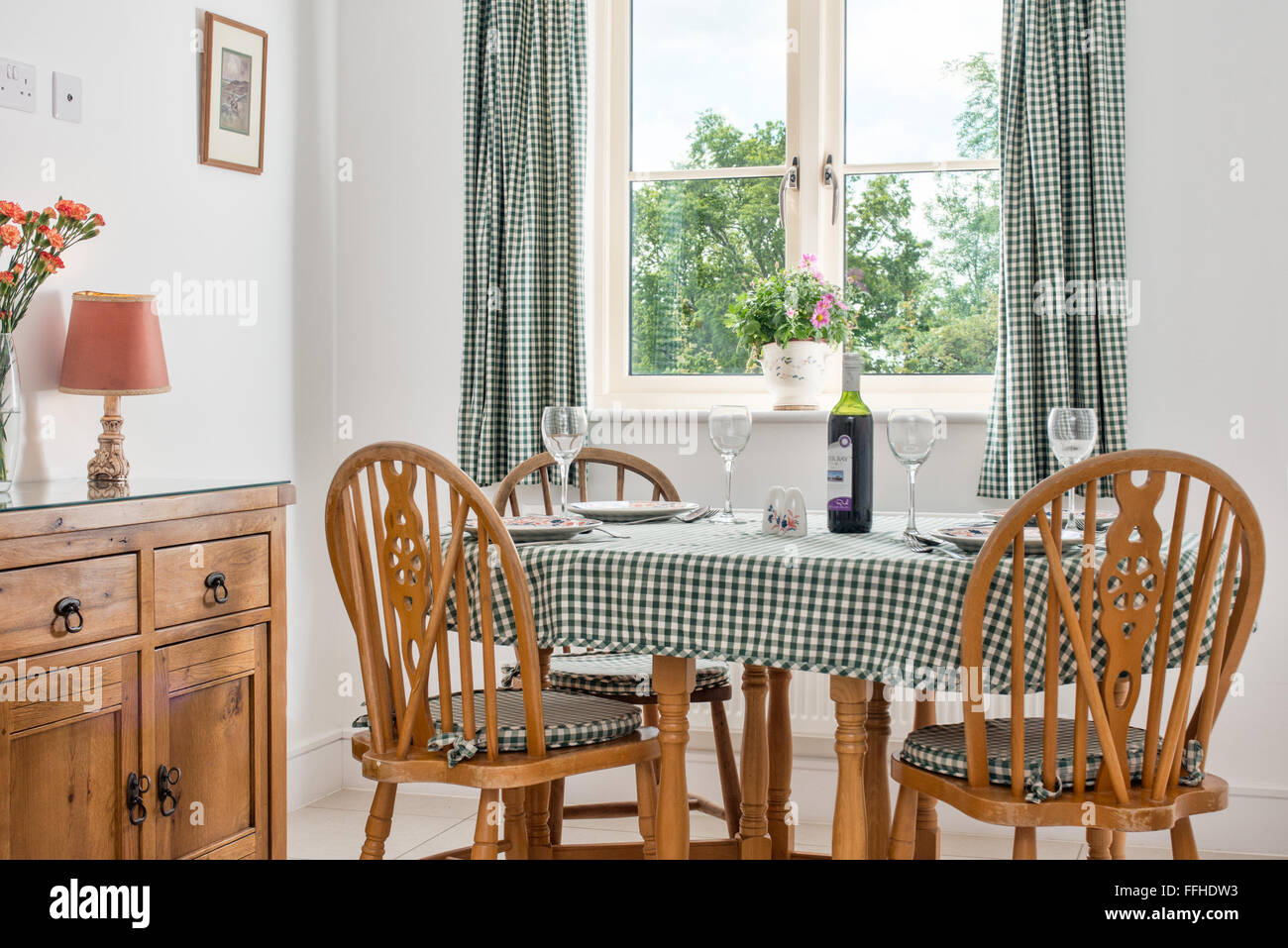 Un paese ding area, mobili in legno di pino, tavolo vestito per la cena con un gingham tovaglie, posate e bicchieri. Foto Stock