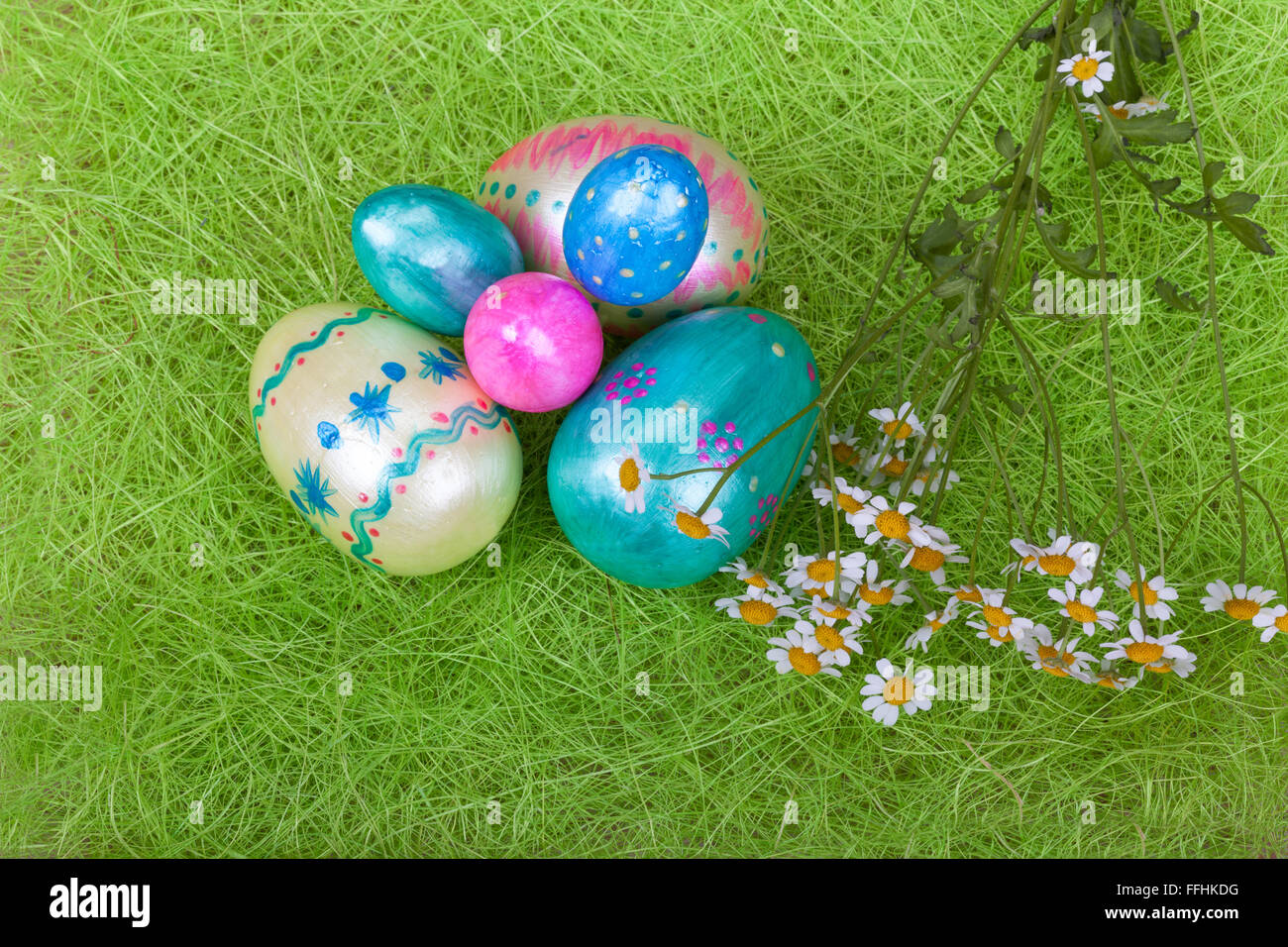 Fresche bianche margherite con le uova di pasqua su erba verde Foto Stock