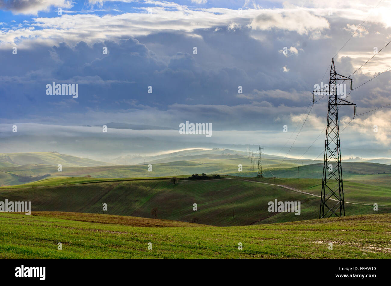 Paesaggio toscano con nuvole e traliccio di elettricità Foto Stock