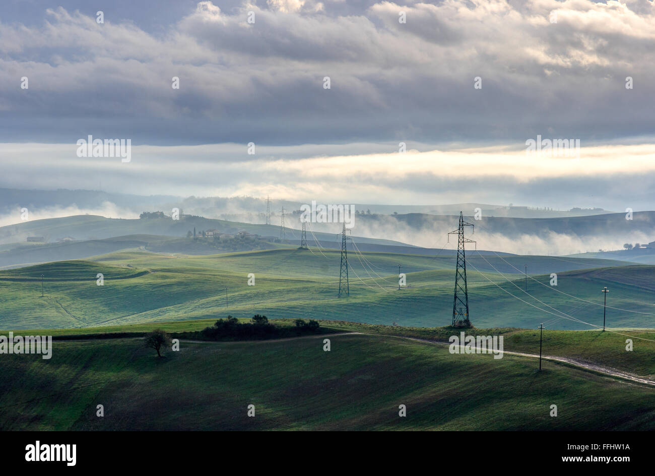 Paesaggio toscano con nuvole e traliccio di elettricità Foto Stock