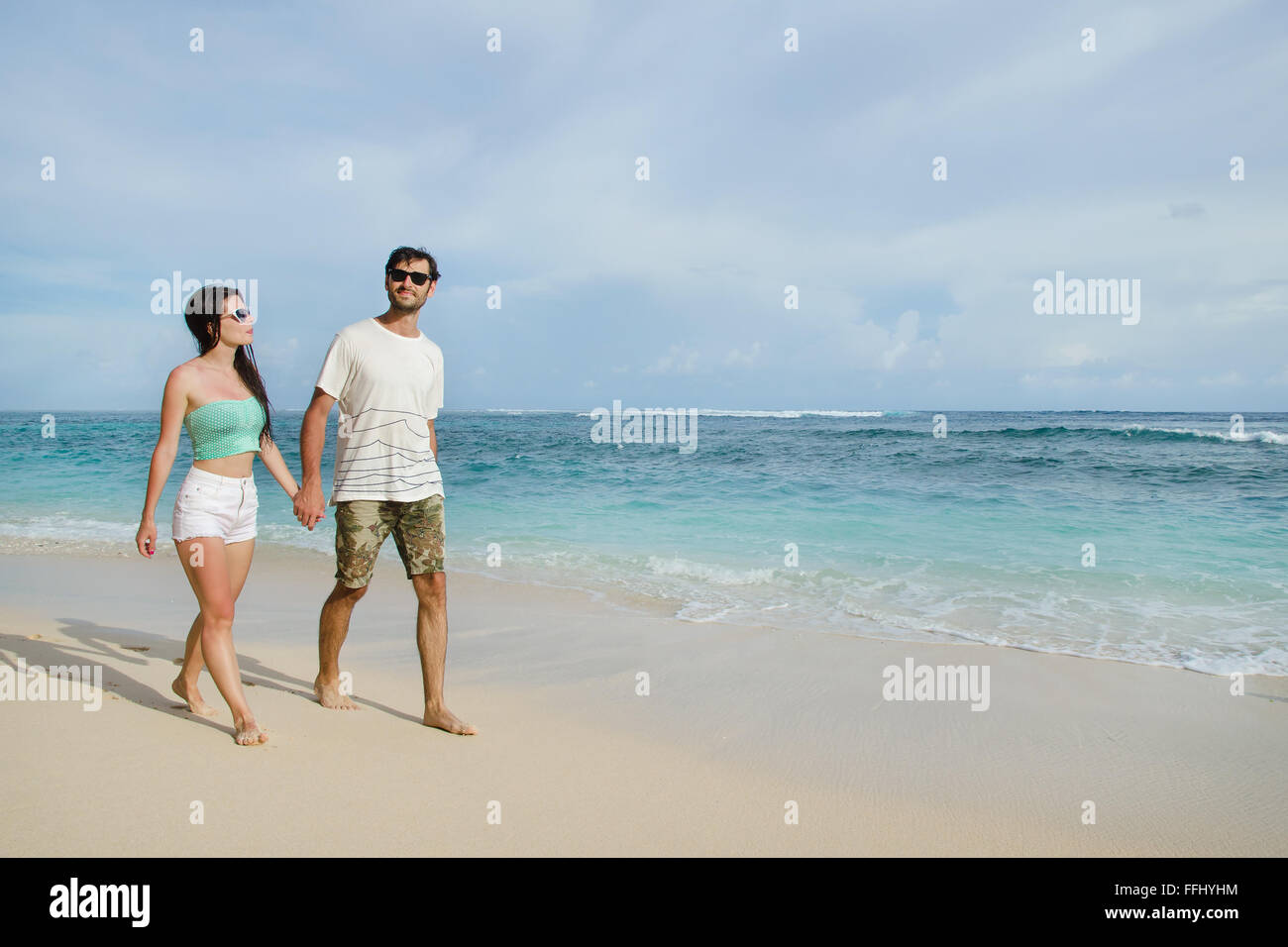 Felice coppia giovane una passeggiata a piedi tenendo le mani sulla spiaggia. Immagine di stock Foto Stock