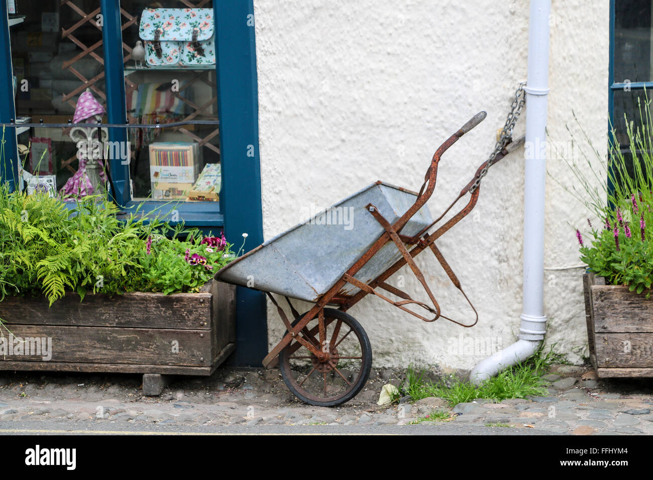 Vecchia carriola di metallo al di fuori del negozio del villaggio, Hawkshead, Lake District, Cumbria, Inghilterra Foto Stock