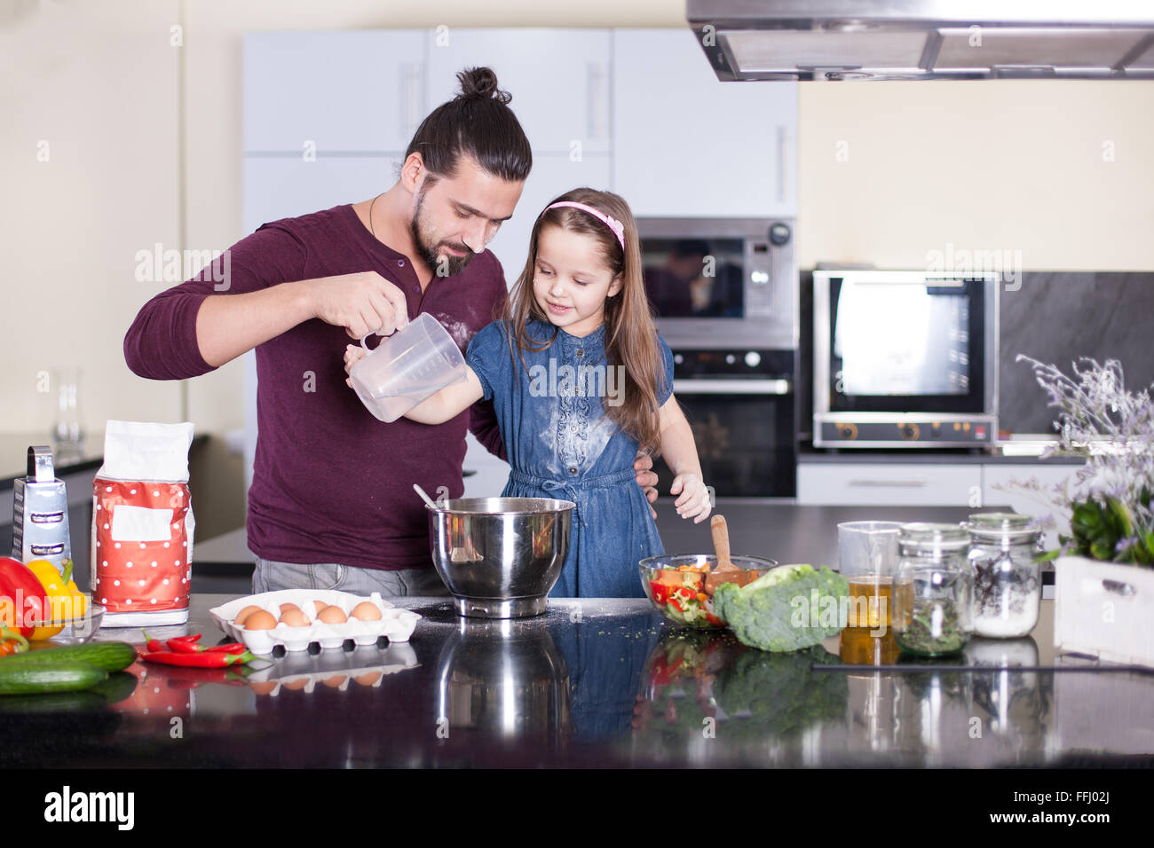 Padre insegna la figlia di cucinare a casa in cucina. Immagine di stock. Foto Stock