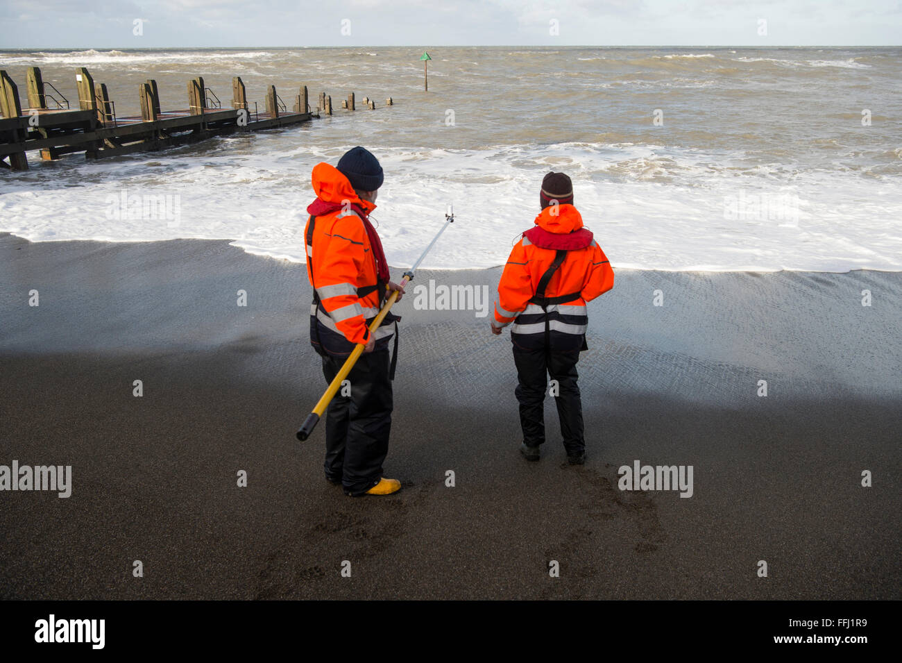 Due scienziati ambientali tenendo la qualità dell'acqua di campioni in mare al largo della spiaggia a Aberystwyth sulla West Wales coast. Acqua di fiume è stato contrassegnato con il batteriofago ed è la distribuzione e la diluizione in mare viene misurato ogni 60 minuti per 48 ore Foto Stock