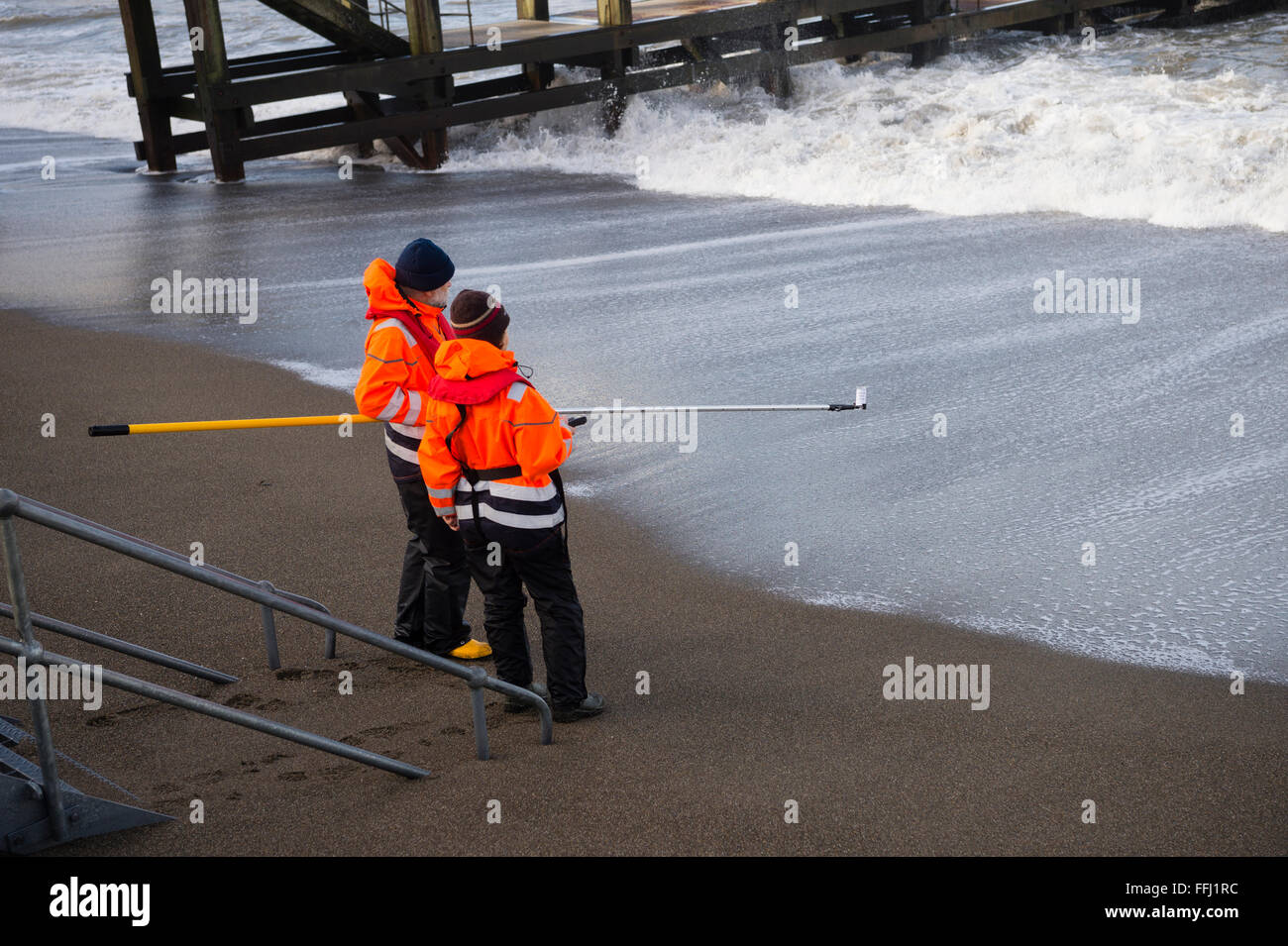 Due scienziati ambientali tenendo la qualità dell'acqua di campioni in mare al largo della spiaggia a Aberystwyth sulla West Wales coast. Acqua di fiume è stato contrassegnato con il batteriofago ed è la distribuzione e la diluizione in mare viene misurato ogni 60 minuti per 48 ore Foto Stock