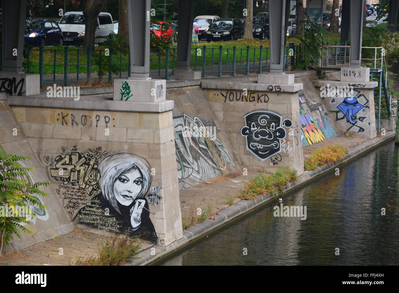 Chiudere i graffiti su una banca di calcestruzzo e il treno via supporto lungo un canale nei pressi di una fermata del treno a Berlino, Germania. Foto Stock