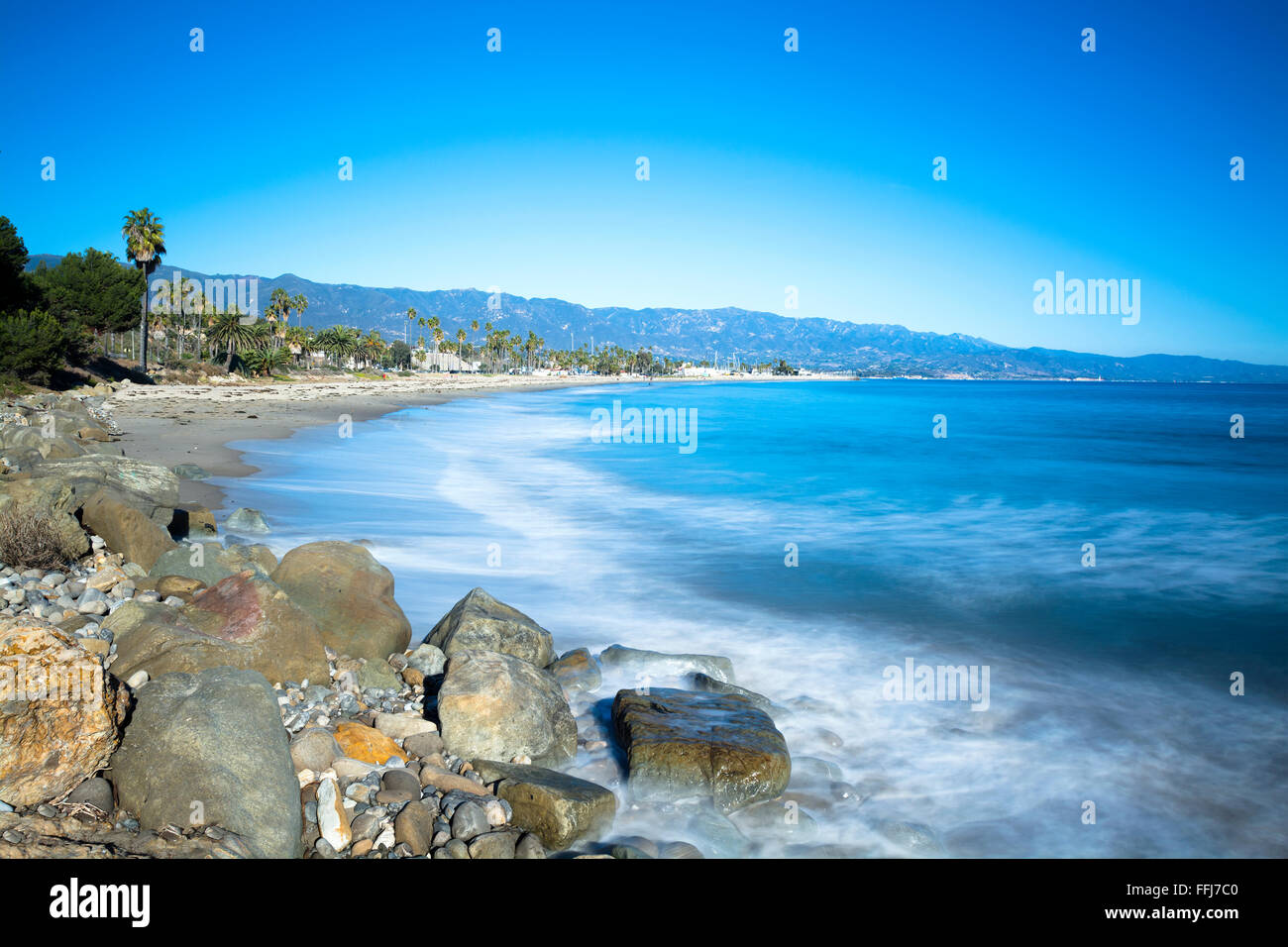 Immagine di una lunga esposizione durante un periodo dove le onde si stanno avvicinando a una spiaggia sabbiosa e rocciosa spiaggia di Santa Barbara in California Foto Stock