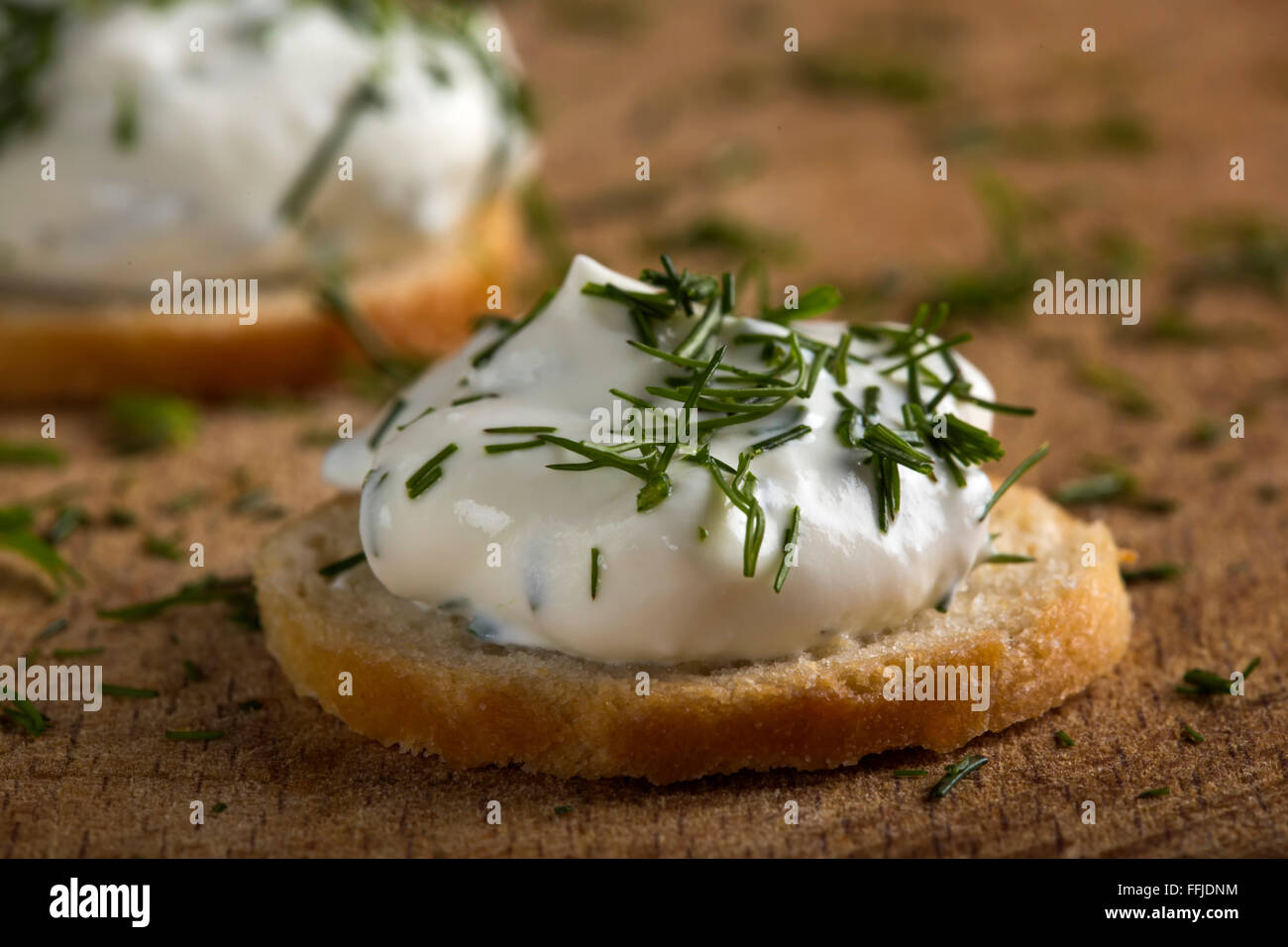 Cracker con crema di formaggio spalmabile topping e aneto su sfondo di legno Foto Stock