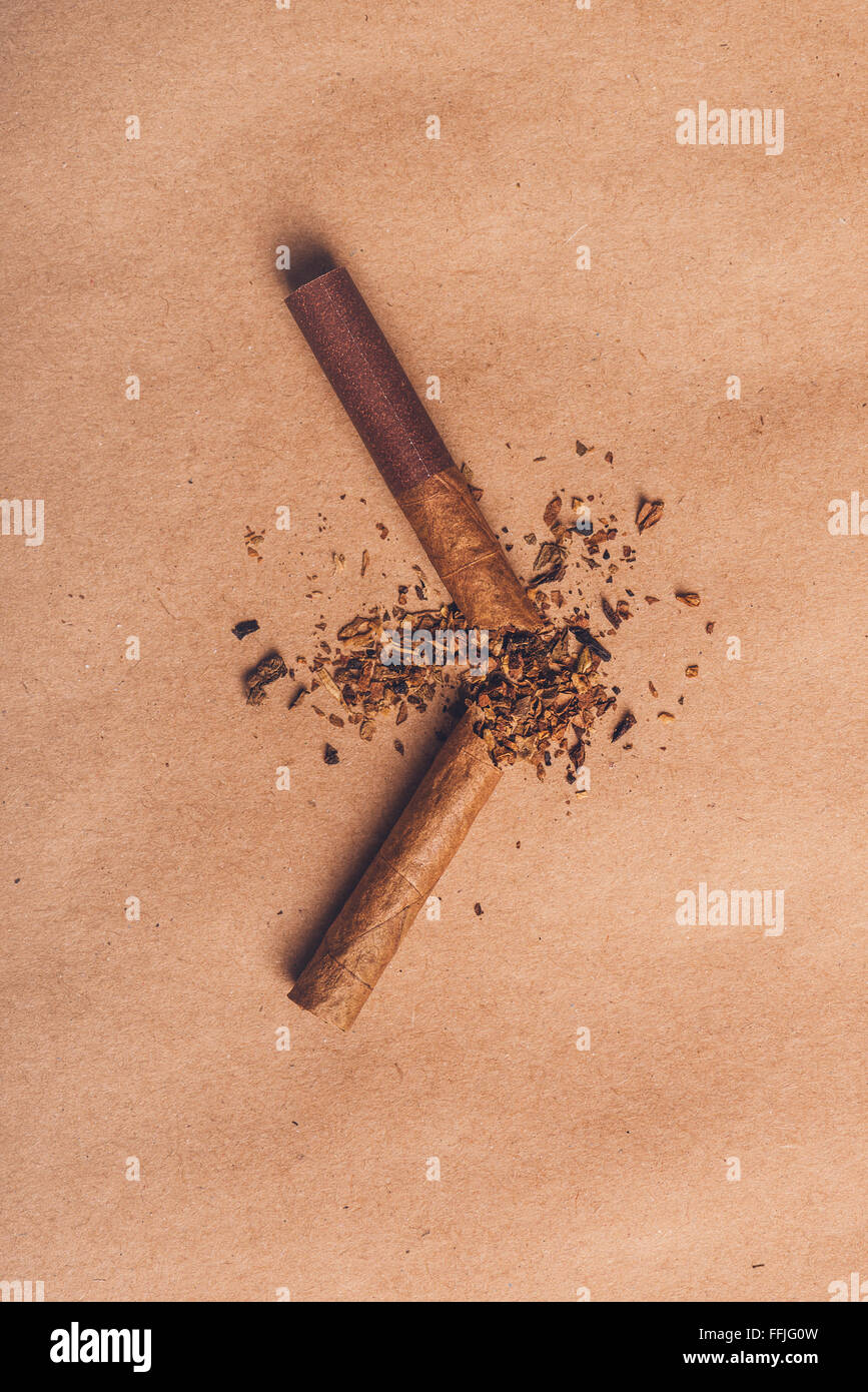 Rotto cigarette top vista su carta marrone, smettere di fumare concetto, calda retrò verticale tono dell'immagine. Foto Stock
