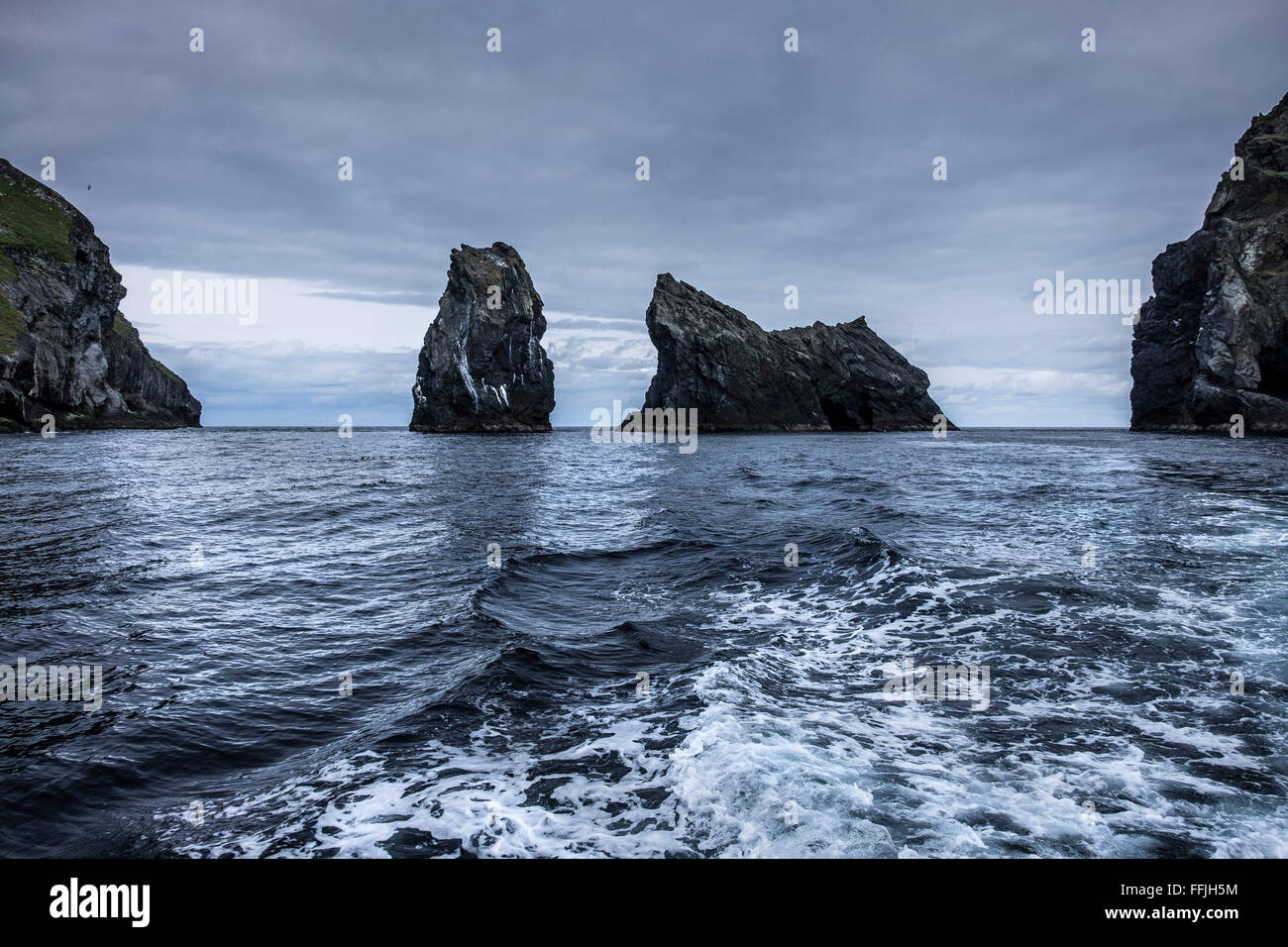 Scia di imbarcazione a motore con sperone roccioso in moody blue sea presso il St Kilda Foto Stock