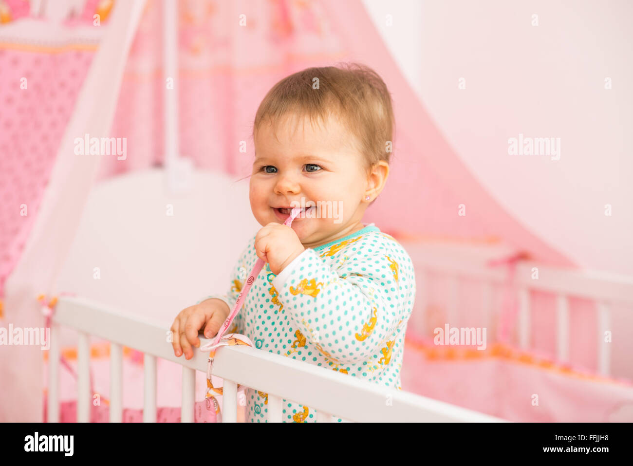 Baby girl è semplicemente in piedi nel letto nella stanza del bambino Foto Stock