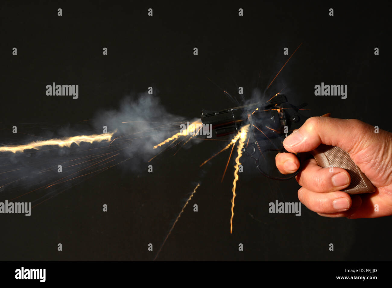Flash e il fumo proveniente da una pistola per mano di essere licenziato. (Pistola giocattolo) Foto Stock