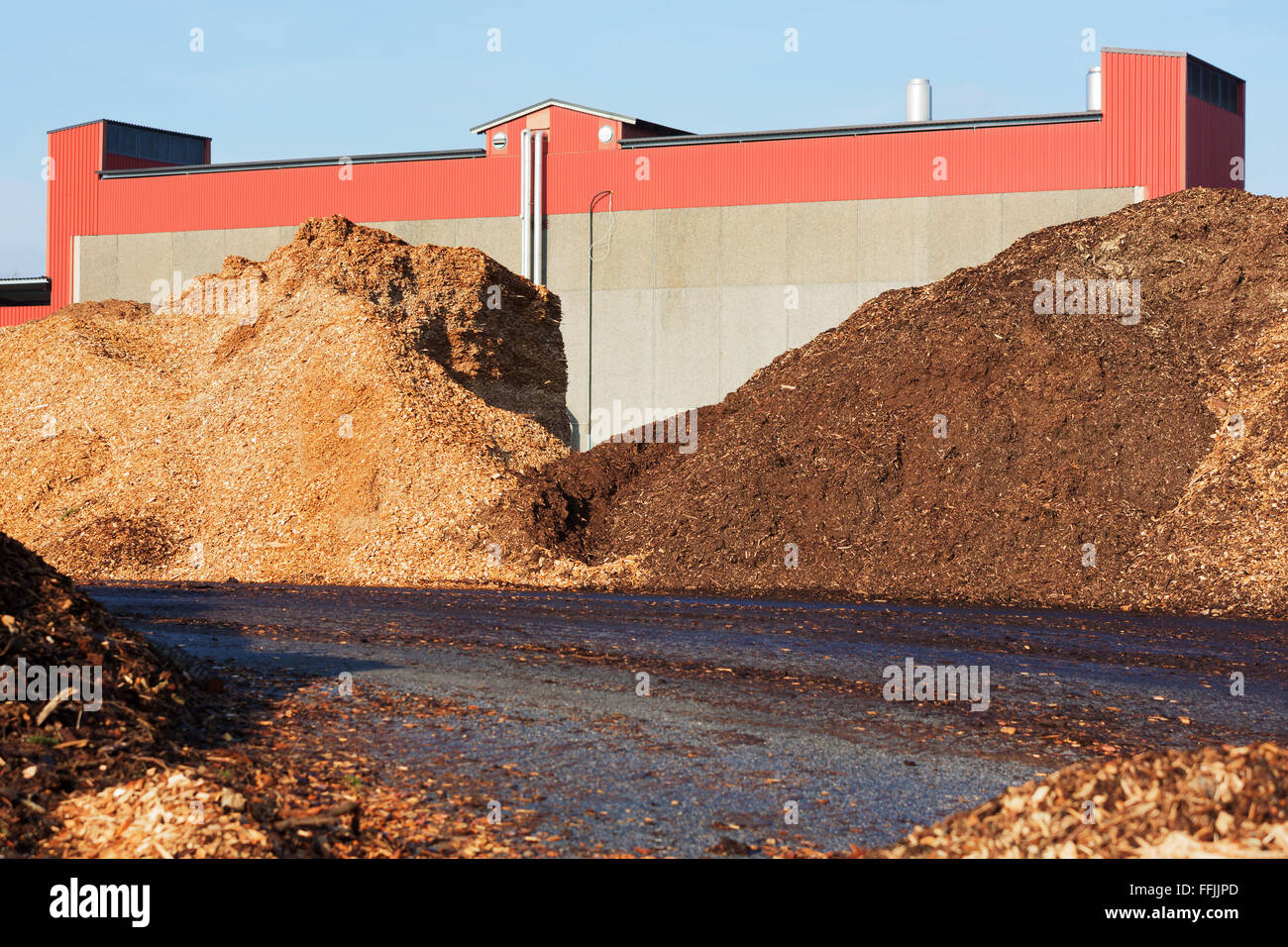 Pile di trucioli di legno usati come biocarburante in impianto di riscaldamento. Edificio industriale in background. Foto Stock