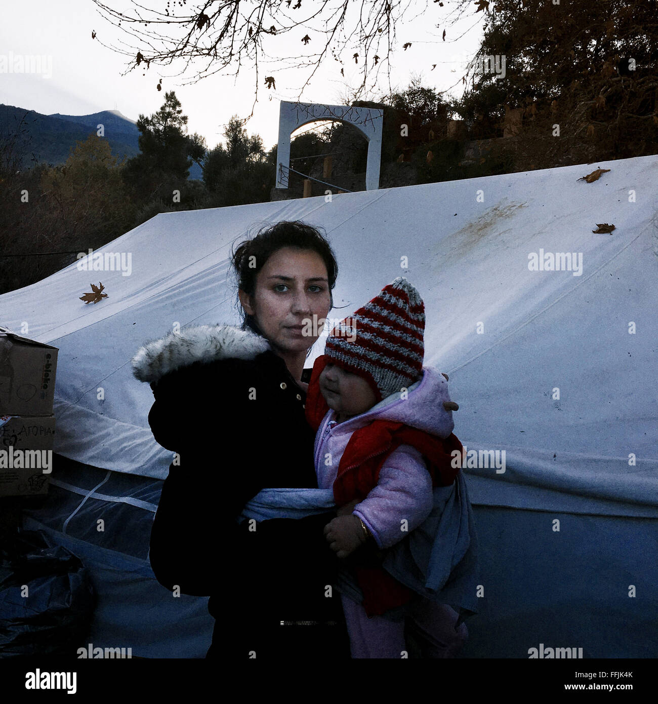 Una donna siriana sorge nella parte anteriore di Platanos tenda, con la baby carrier realizzato da una iniziativa di solidarietà per il bambino Foto Stock