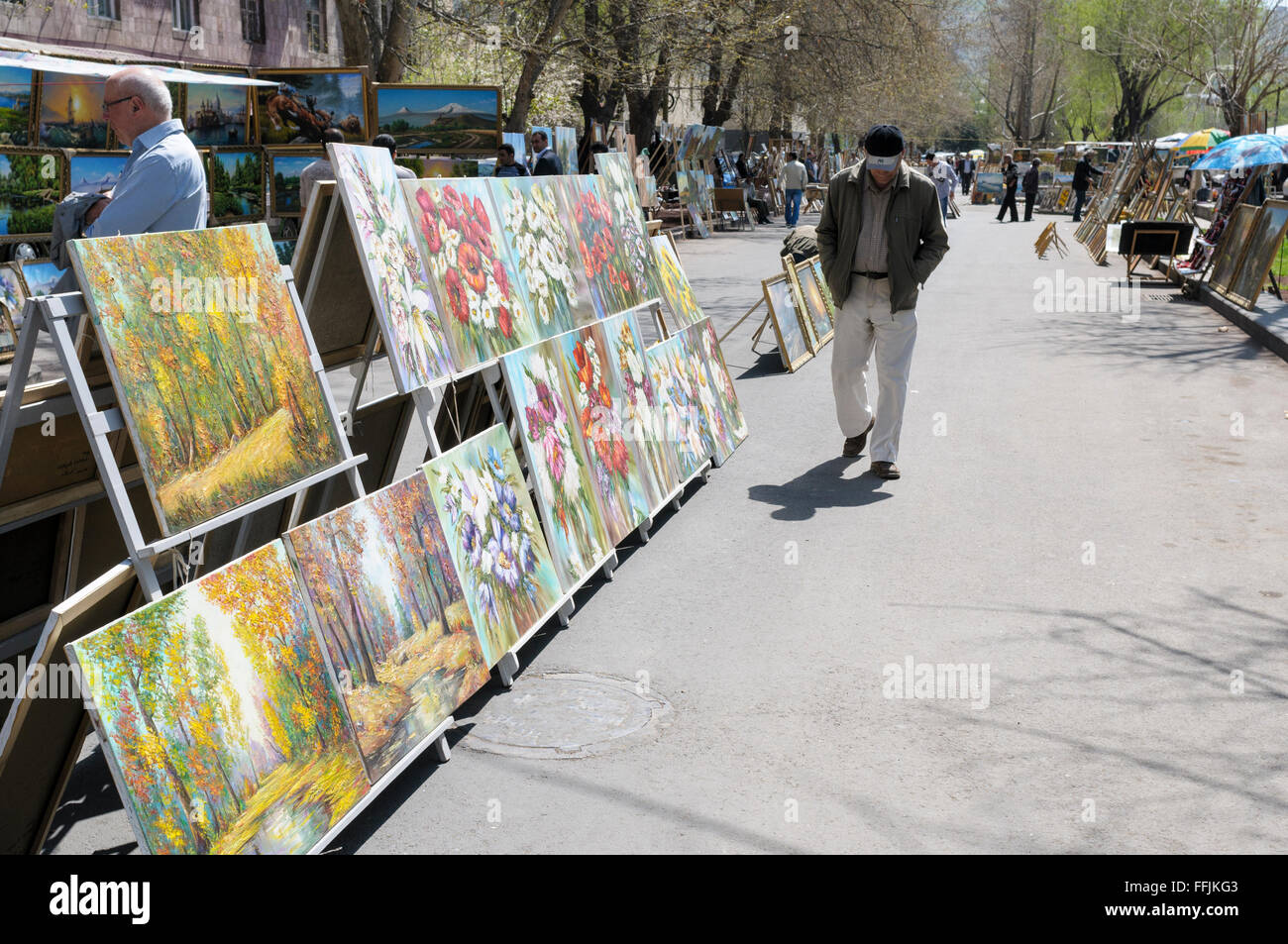 Uomo che cammina passato arte in vendita al vernissage open-air mercatino delle pulci, Yerevan, Armenia Foto Stock