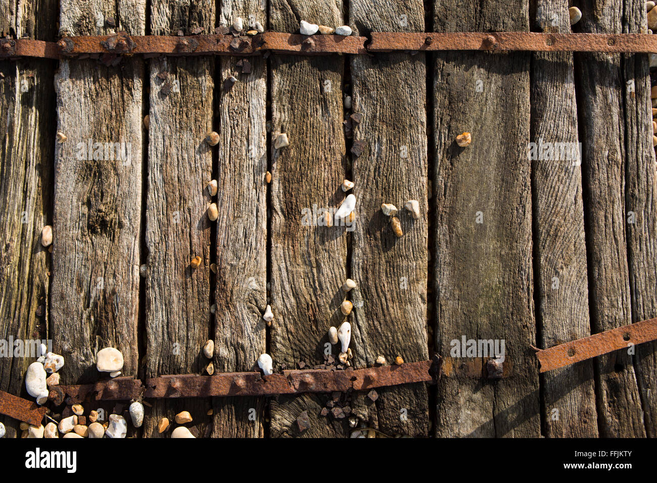 Una vecchia passerella in legno con ciottoli e sabbia Foto Stock