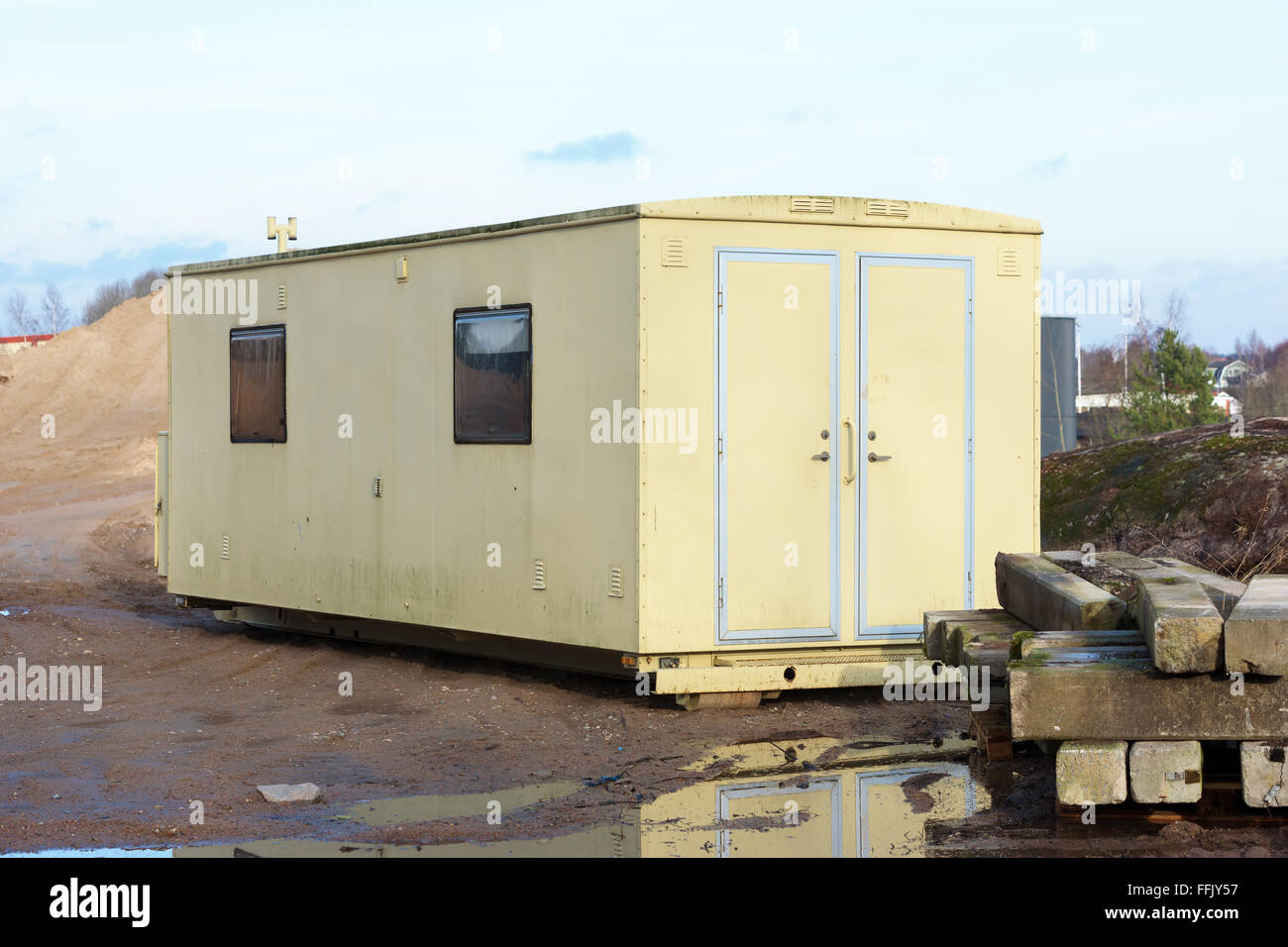 Un giallo di lavoro mobile capannone a bagnato e fangoso terreno sito in costruzione. Foto Stock