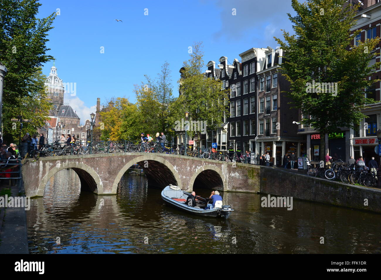 Un piccolo canale viaggi in barca sotto un ponte pedonale nel quartiere a luci rosse di Amsterdam, Paesi Bassi. Foto Stock