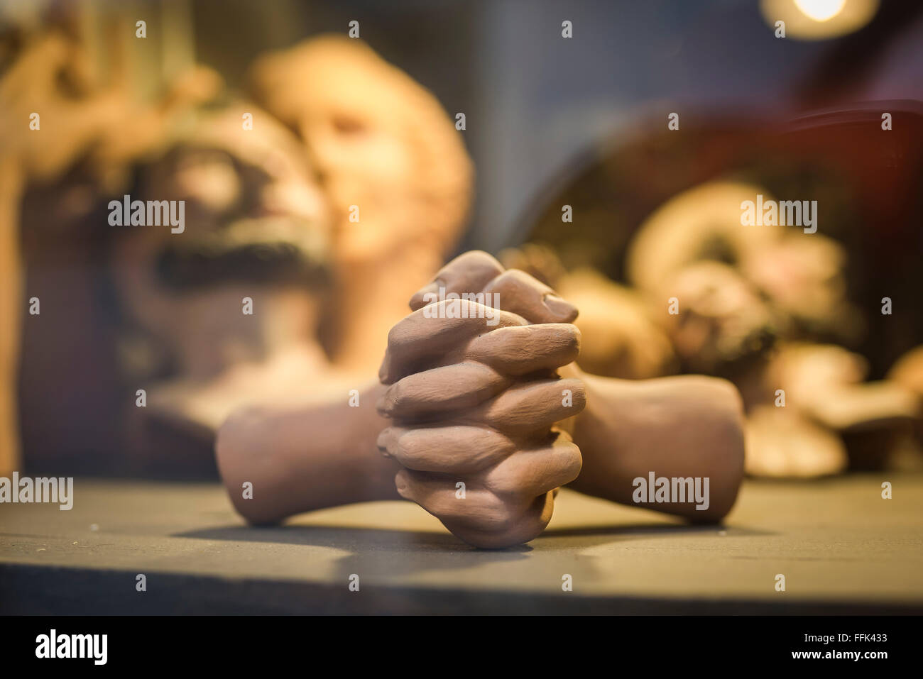 Mani preghiera, vista di un paio di mani di terracotta agganciate come in preghiera, come parte di una mostra in una vetrina di scultori a Napoli. Foto Stock