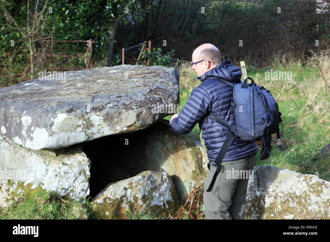 Uomo che guarda dentro la sepoltura del Neolitico tomba dal 3000 BC in Douglas Park, Largs, Scozia Foto Stock