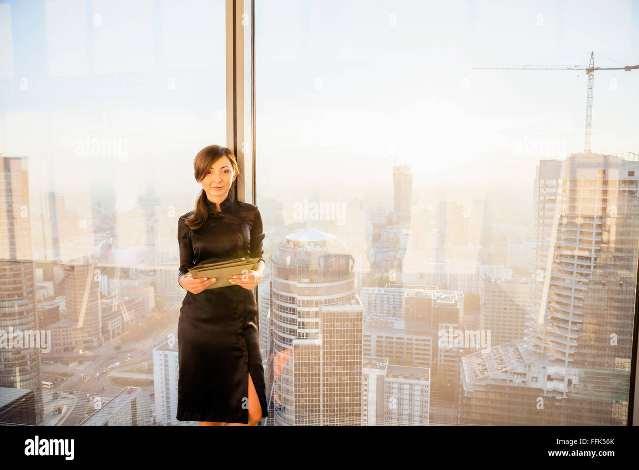 Architetto femmina in ufficio con urban skyline in background Foto Stock